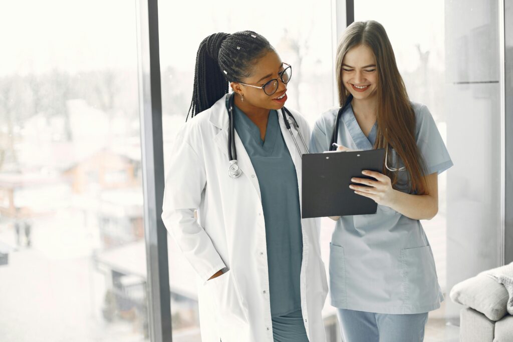 Two female healthcare professionals discussing documents in a bright medical setting. seo for healthcare
