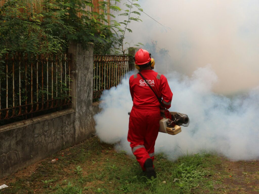 pexels-photo-19789837-19789837 A pest control worker fogging in an outdoor space with smoke to eliminate pests.