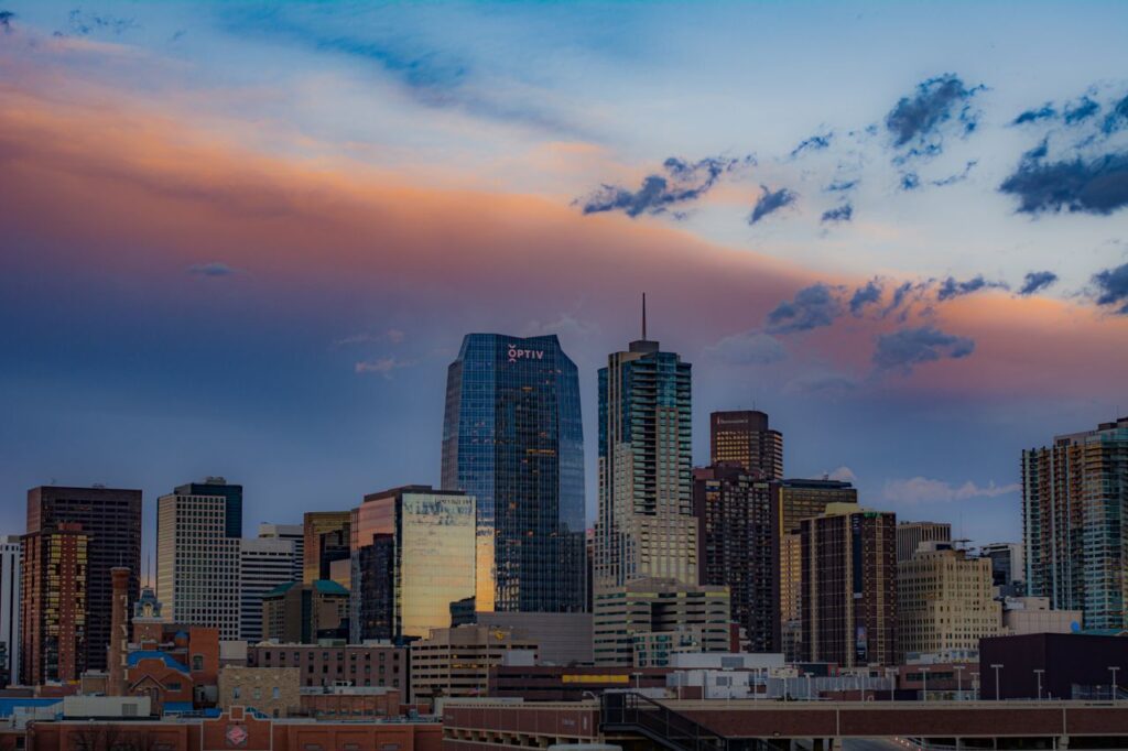 pexels-photo-16108565-16108565 Stunning view of Denver's cityscape with skyscrapers under a colorful sunset sky.